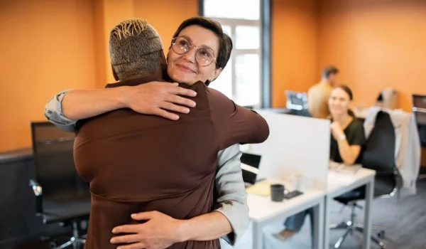 Dos personas abrazándose en una oficina.