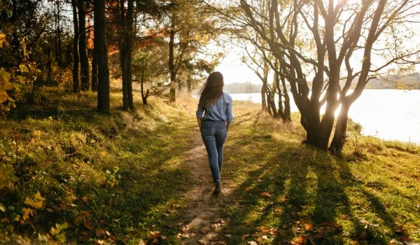 Mujer caminando afuera en un bosque junto a un lago