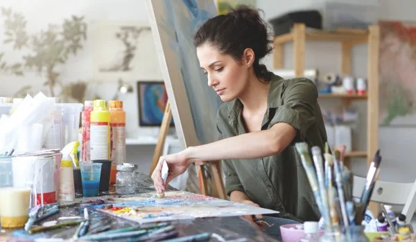 Mujer trabajando en una pintura con varios pinceles para el dolor