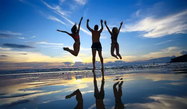 Tres personas saltando de alegría en una playa