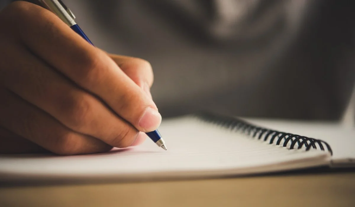 Una mano escribiendo en un cuaderno