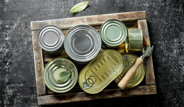 Varias latas en una caja de madera con un abrelatas