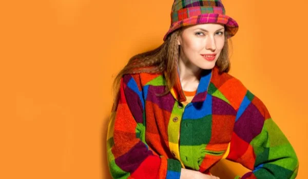 Una mujer con ropa multicolor, una camisa y un sombrero de varios colores.