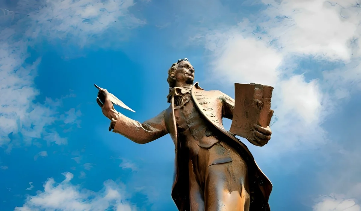 Estatua de un pensador sosteniendo un libro y un bolígrafo