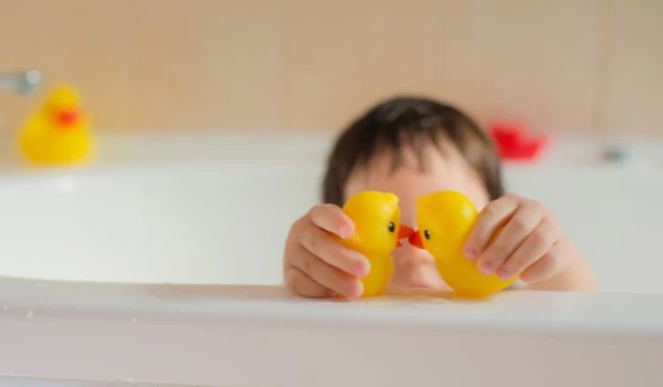 Niño jugando con dos patitos de goma