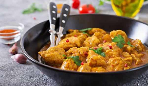 Un plato de pollo al curry con dos cucharas