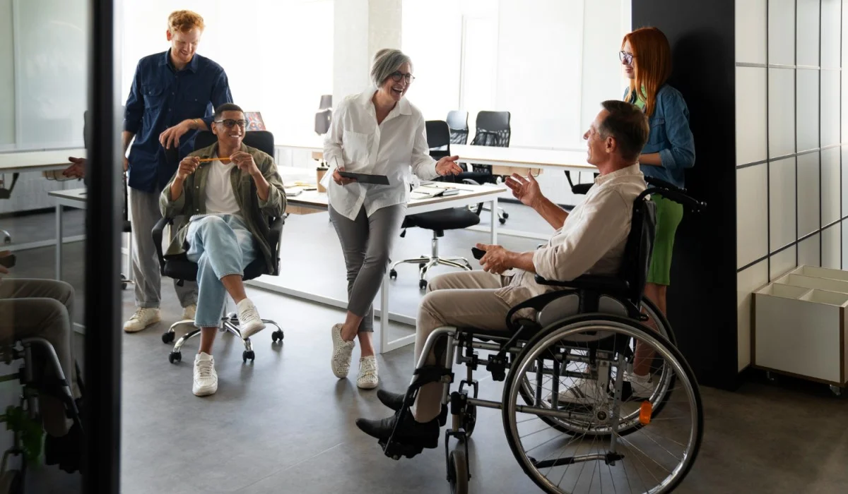 Una oficina con cuatro personas y un hombre en silla de ruedas.