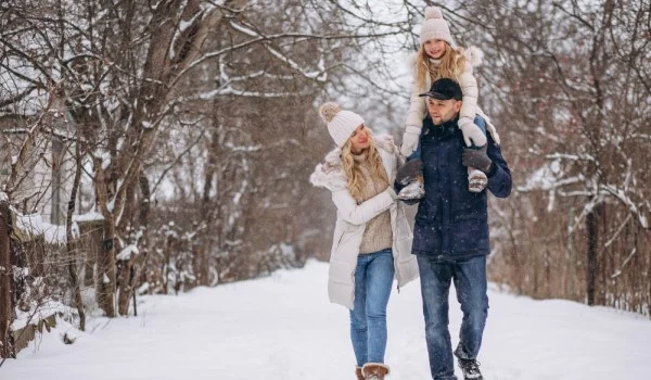 Una pareja con su hija caminando en la nieve.