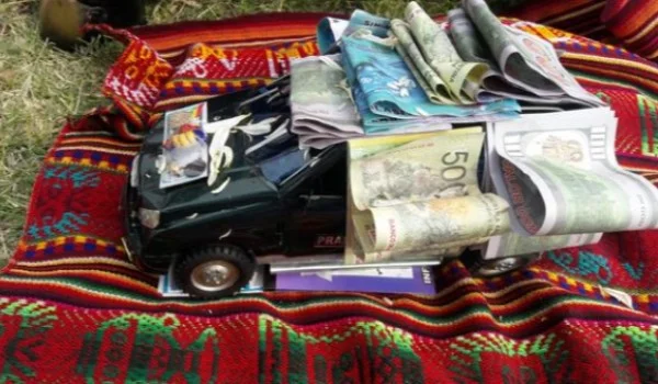 Dinero y una figura de un auto sobre un poncho boliviano